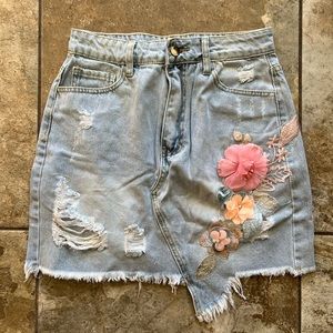 Distressed light blue jean skirt with floral appliqué medium